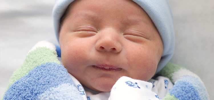 Lächelndes Baby nach der Geburt mit einer Nabelschnurblutspende